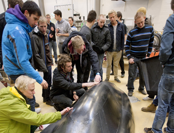 DTU-studerende har brugt vinteren på at optimere universitetets økobil, som forhåbentlig giver baghjul til de øvrige deltagere i årets Shell Eco-marathon. Blandt andet har bilen fået nyt design, og man har erstattet det tungere glasfibermateriale med kulfiber. Da de glade projektdeltagere bærer bilens overdel ind i varmen på DTU, er der ikke tale om et tungt løft, da overdelen kun vejer 6031 gram. Foto: Mikal Schlosser