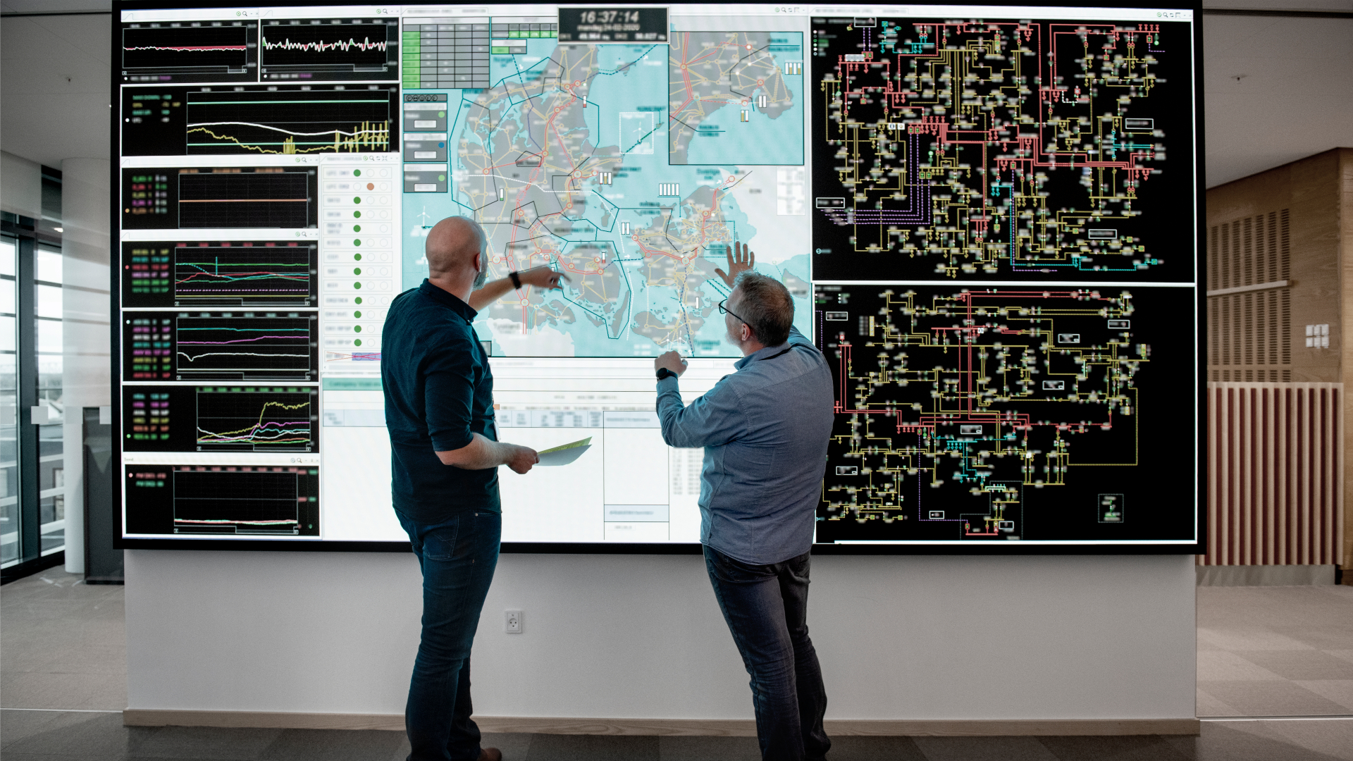To mænd står foran en storskærm med et Danmarkskort og data fra energinettet