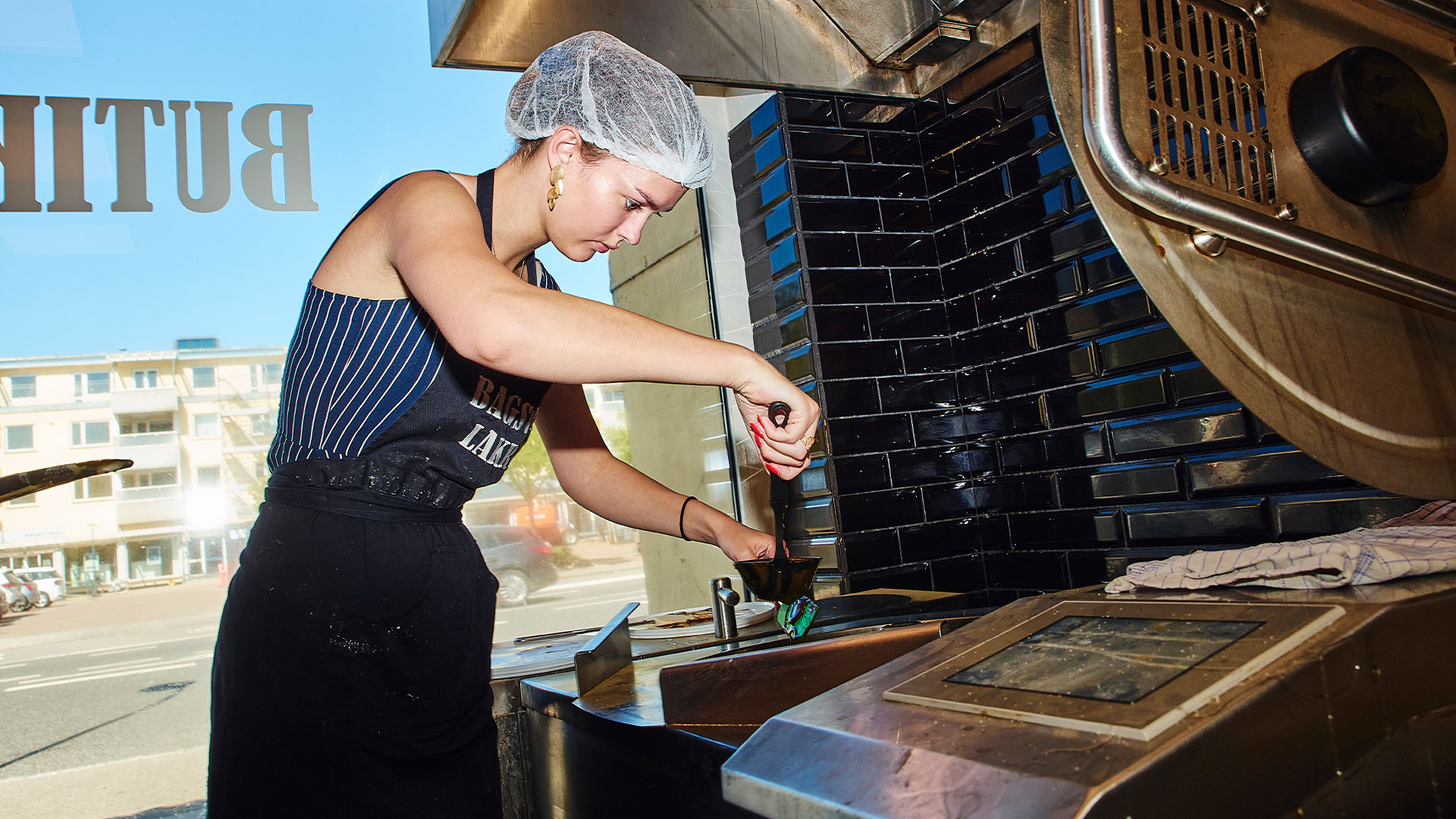 Ung kvinde står ved produktionsmaskiner i Bagsværd Lakrids' produktionslokaler. Foto: Magnus Møller