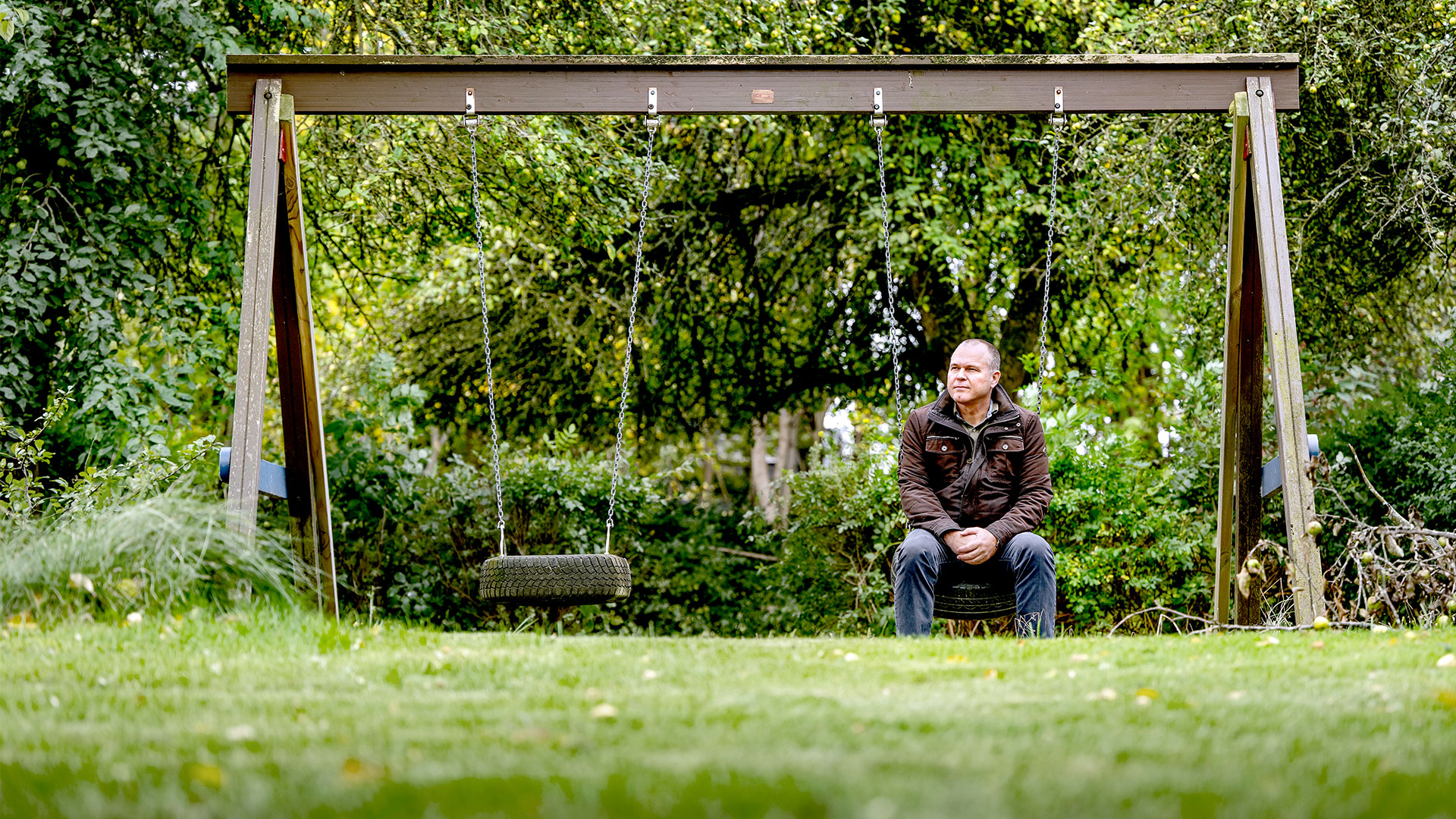 Mand sidder på den ene af to gynger i et gyngestativ. Foto: Bax Lindhardt