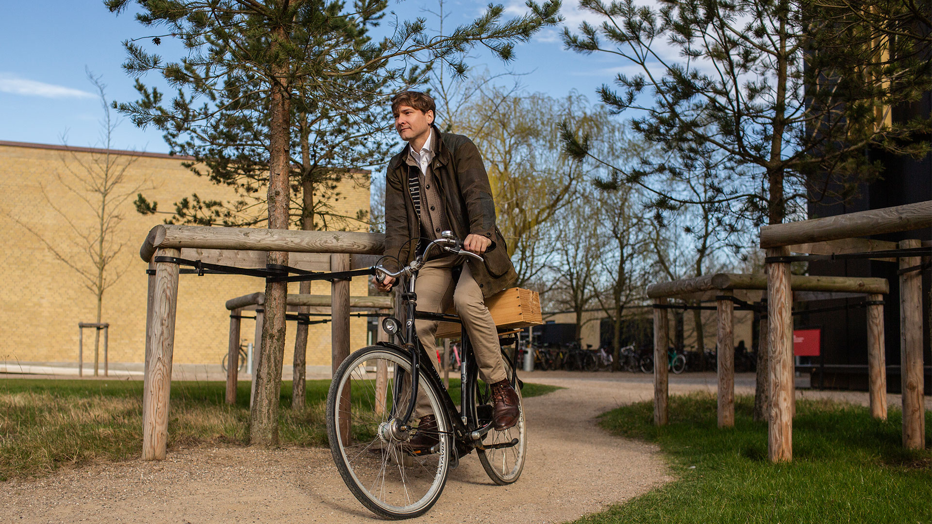 Mand cykler gennem noget beplantning i et bebygget område. Foto: Ditte Valente