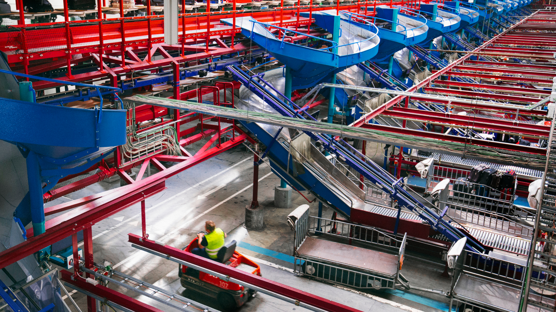 Bagagehåndteringen under Københavns Lufthavn med et sirligt system af slisker og transportbånd, hvor kufferter bliver transporteret frem og tilbage.