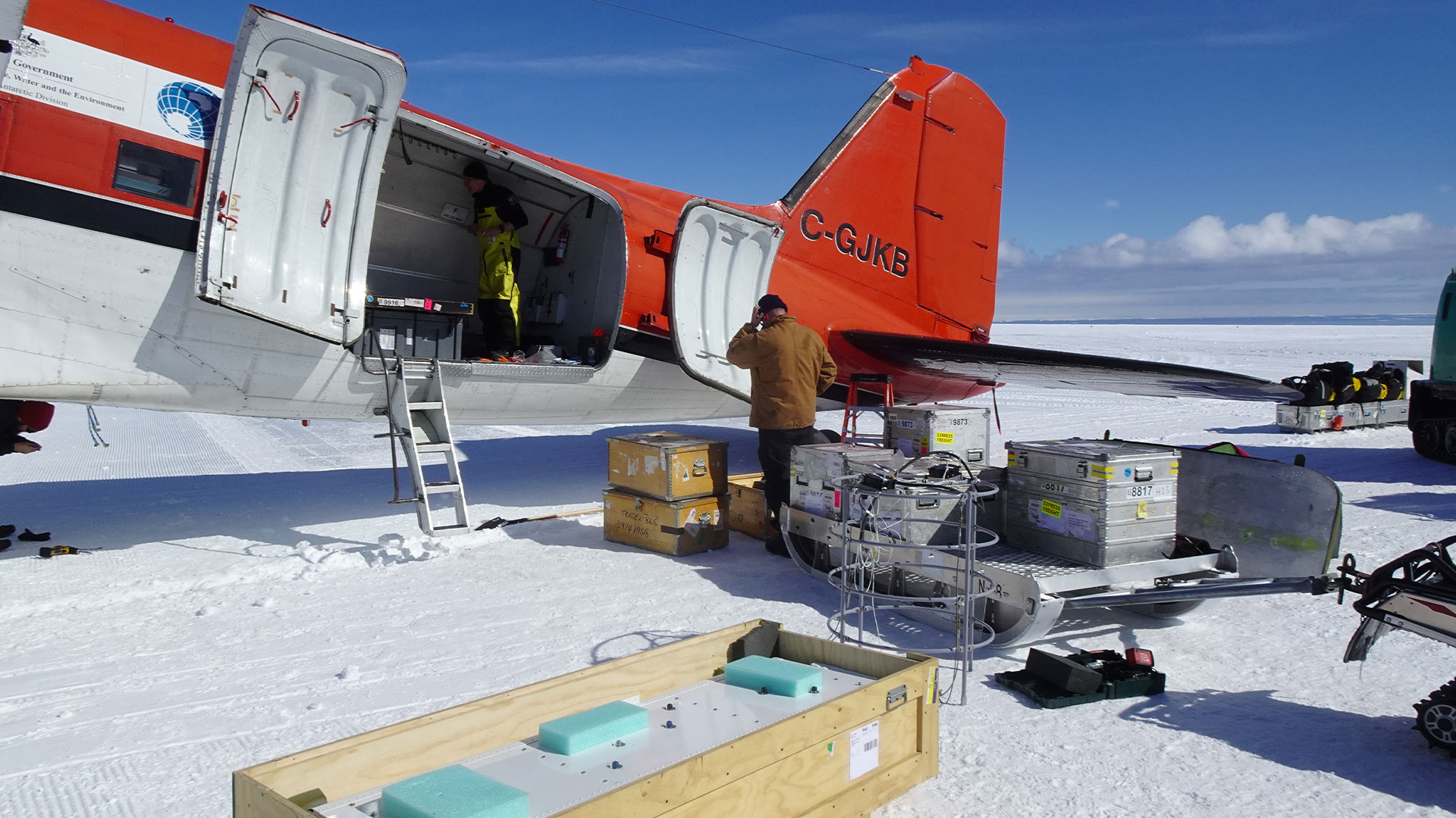 A propeller aircraft is sitting on the ice in Antarctica while being loaded.